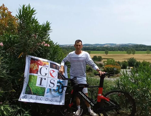 Le triathlète gersois Régis Brun pose avec son vélo et le drapeau du Gers - Agrandir l'image (fenêtre modale)